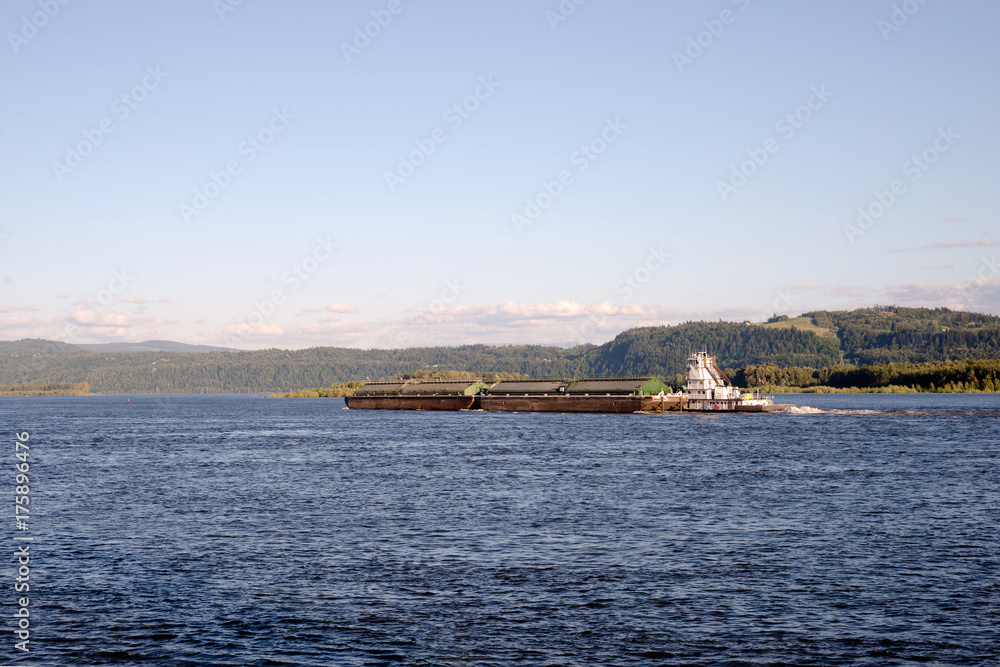 The tug pushes two coupled barges along the wide Columbia River