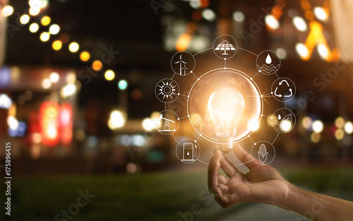 Hand holding light bulb in front of global, show the world's consumption with icons energy sources for renewable, Ecology concept Fototapet