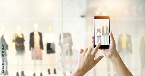 Hands using mobile smart phone and take a photo on display of a clothing store, online shopping concept