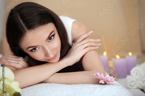 Beautiful young woman relaxing in jacuzzi hot tub at spa. Attractive female tourist is surrounded with lit candles. Smiling woman is pampering herself during vacation.