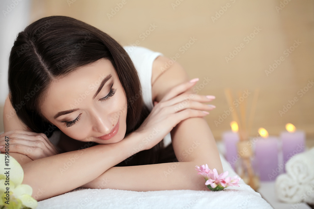 Beautiful young woman lying on massage table in spa salon Beautiful young woman lying on massage table in spa salon