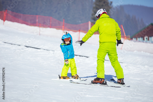 Lesson at skiing school: instructor teaching little skier how to make turns
