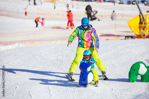 Father teaching little son to ski in children's area on winter resort