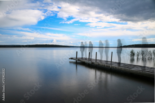 Silhouette of a woman walking on a pier at the lake
