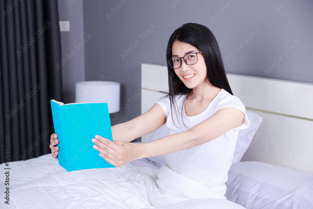 woman reading a book on bed in bedroom at home woman reading a book on bed in bedroom at home