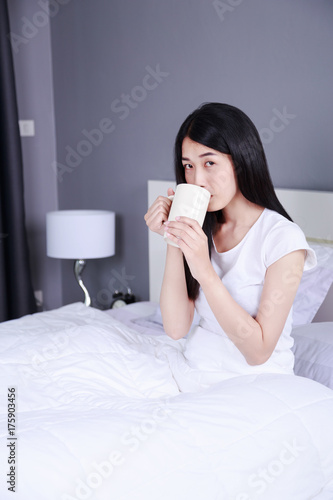 woman on bed with a cup of coffee in bedroom