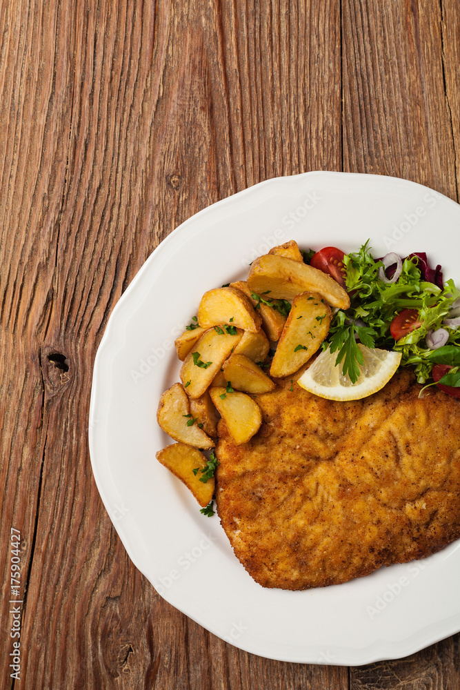 Chicken schnitzel, served with roasted potatoes and salad. Chicken schnitzel, served with roasted potatoes and salad.