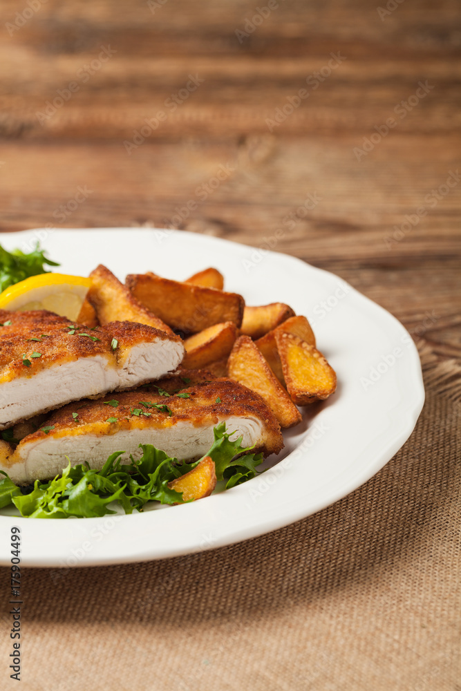Chicken schnitzel, served with roasted potatoes and salad. Chicken schnitzel, served with roasted potatoes and salad.