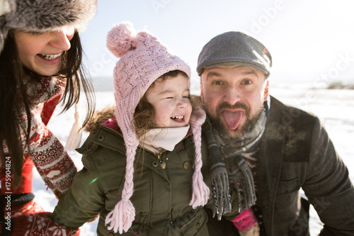 Father  mother and their daughter having fun in winter nature.