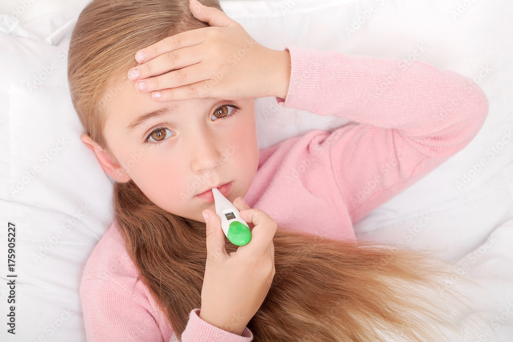 Sick girl lying in bed with a thermometer in mouth Sick girl lying in bed with a thermometer in mouth