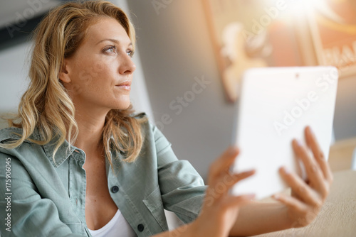 Woman sitting at home websufing on internet with digital tablet