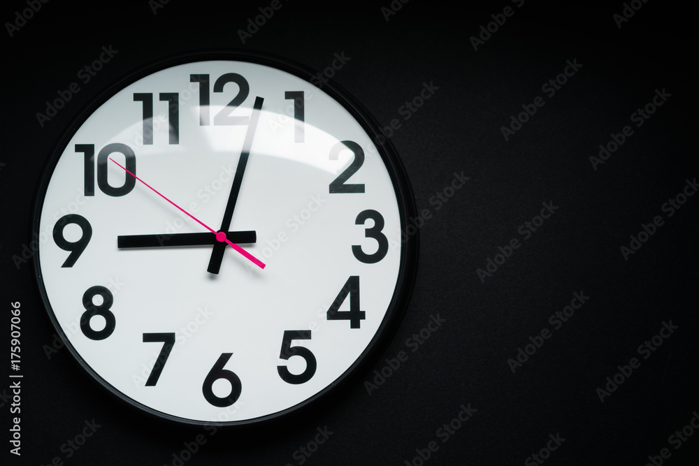 Realistic classic dark and white round wall clock, isolated on black background. selective focus. Realistic classic dark and white round wall clock, isolated on black background. selective focus.