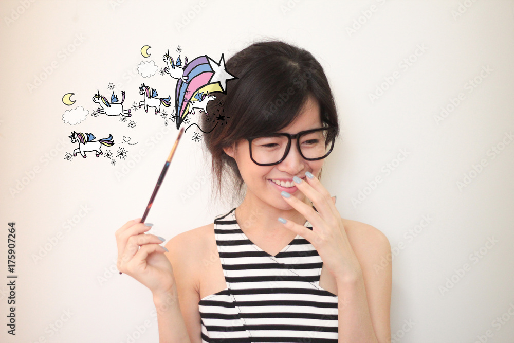Young asian artist woman wearing glasses holding pain brush with unicorns and rainbows doodles illustration Young asian artist woman wearing glasses holding pain brush with unicorns and rainbows doodles illustration