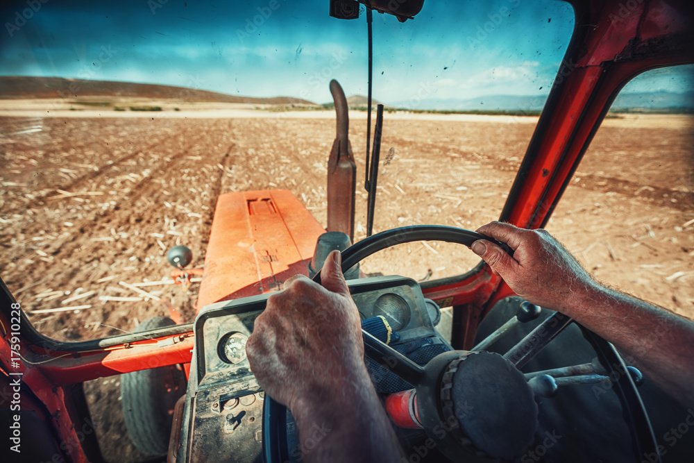 Obraz premium Closeup hands of farmer, sits inside in the tractor cabin
