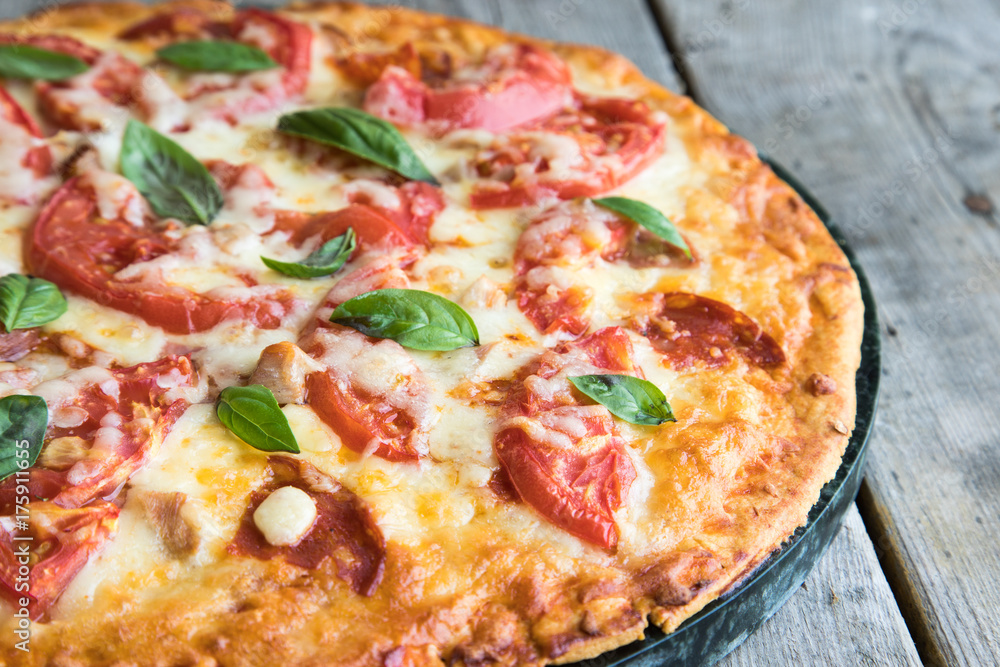 Hot Homemade Pepperoni Pizza on a rustic wooden table. Pizza with tomato, cheese and basil with copy space Hot Homemade Pepperoni Pizza on a rustic wooden table. Pizza with tomato, cheese and basil with copy space