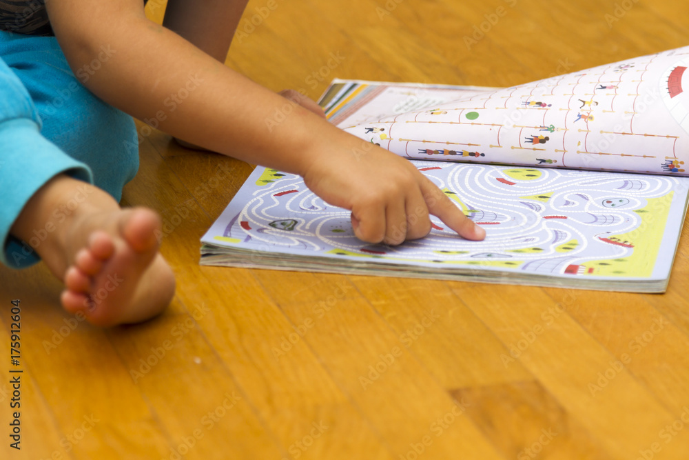 Cute little boy sitting on floor reading in classroom at the nursery school Cute little boy sitting on floor reading in classroom at the nursery school