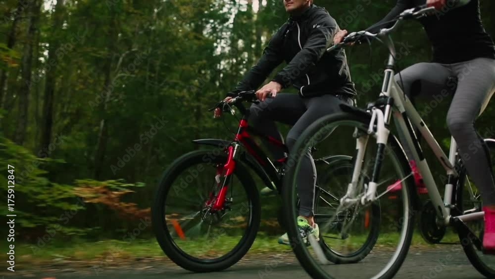 Steadicam shot of mountain biking couple riding on bike trail at sunset doing high. Steadicam shot of mountain biking couple riding on bike trail at sunset doing high.