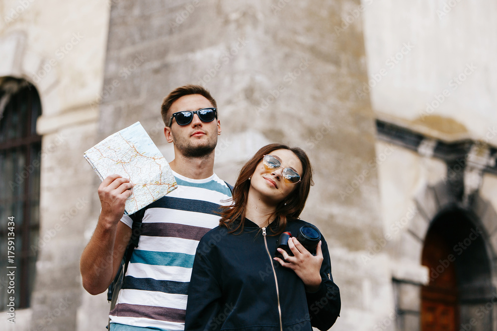 Woman works with camera while man stands with touristic map somewhere in the city Woman works with camera while man stands with touristic map somewhere in the city