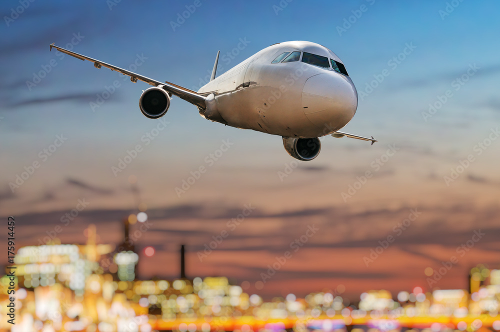 Fototapeta premium Airplane is flying over city at sunset.