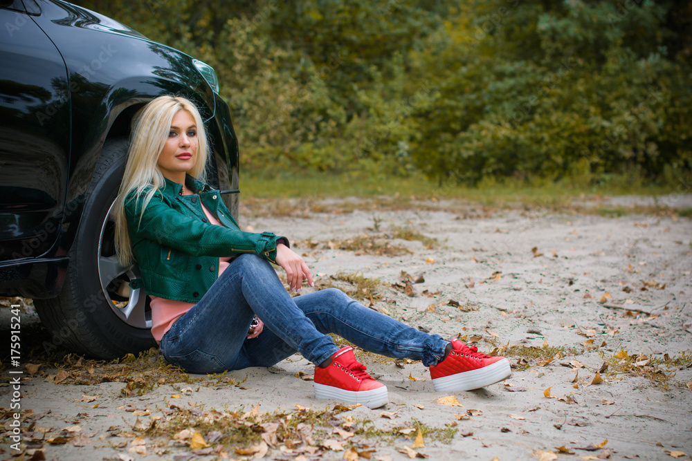 Beautiful and sexy young woman in leather green jacket, jeans and red  sneakers walk in the