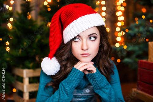 Woman in a santa hat on a blurred Christmas background.