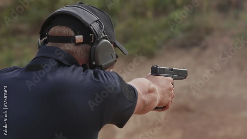 FullHD footage. Man in headphones shoots a pistol on the target.