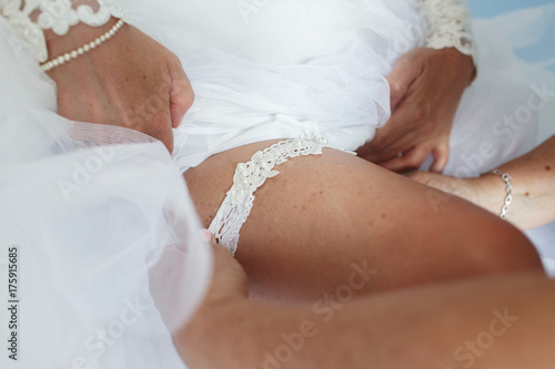 Seductive bride puts on white garter