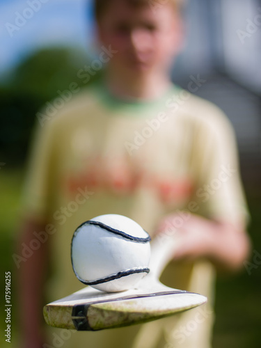 Young boy holds up a hurling stick (camán) and ball (sliotar)