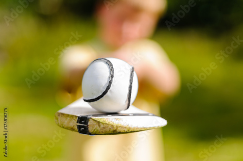 Boy holding up a hurling bat and sloitar (ball)