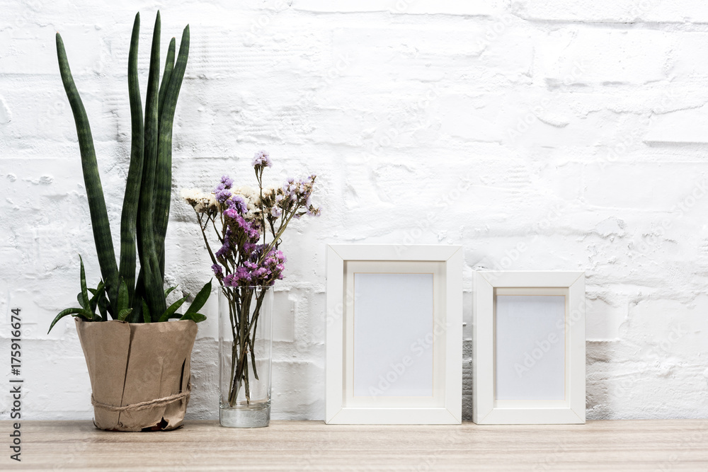Fototapeta premium empty photo frames and flowers on table
