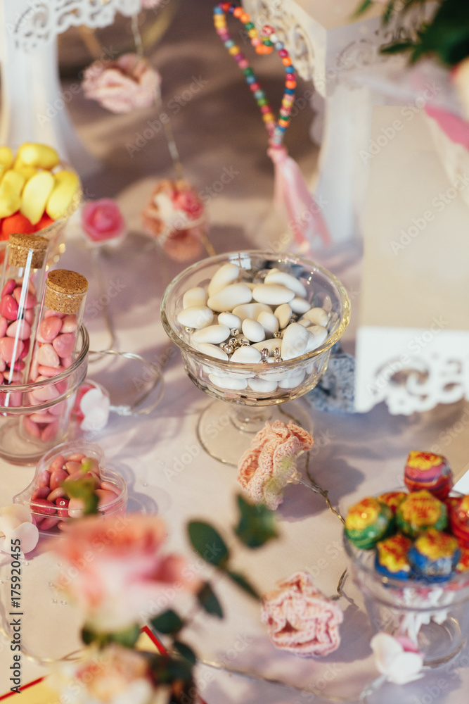 Glass bowls with colorful chocolate pills stand on wedding candy bar