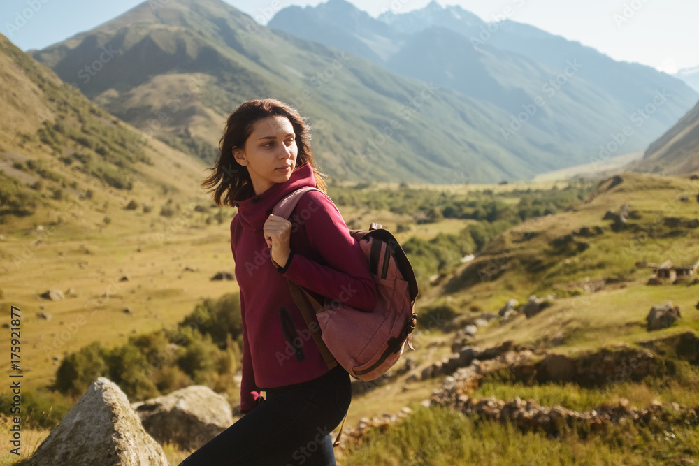 a young woman traveler with backpack enjoying view of autumn mountains