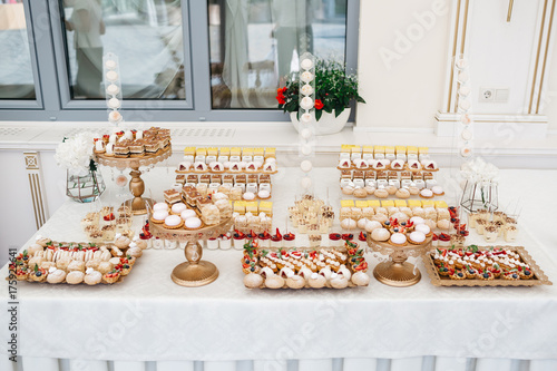 Golden plates with delicious desserts stand on white candy bar