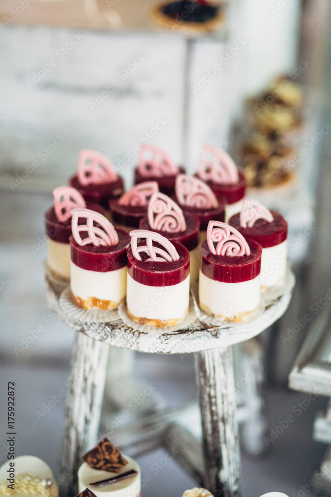Cold desserts with berries and white cream stand on wooden chair on candy bar