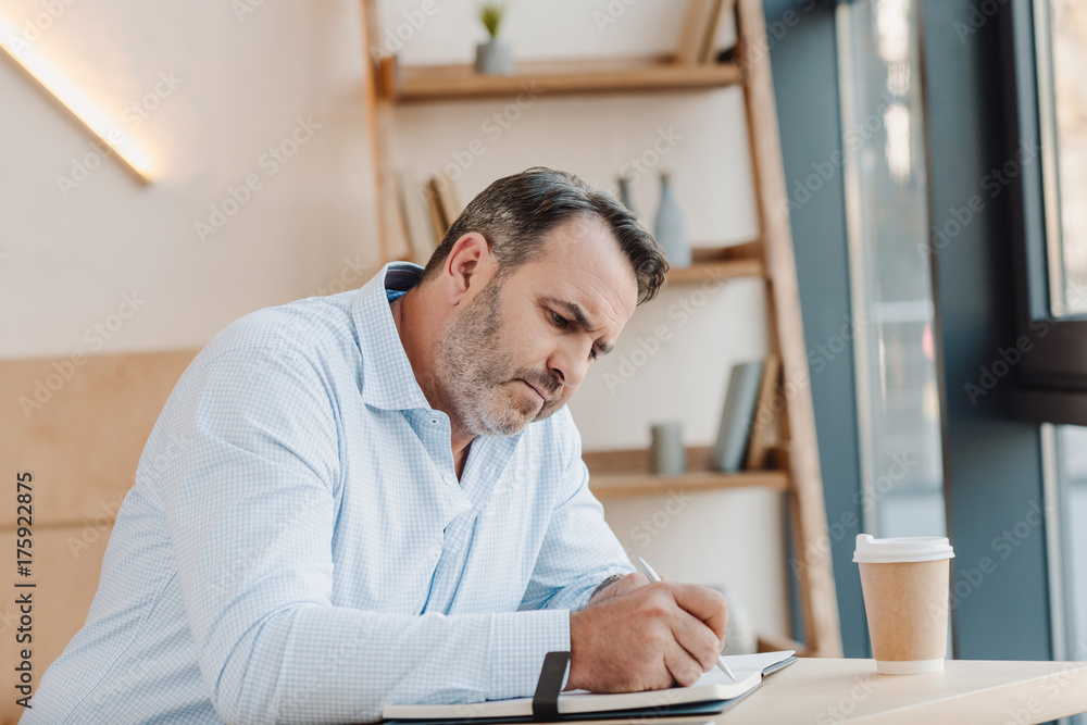 Naklejka premium businessman writing in notebook