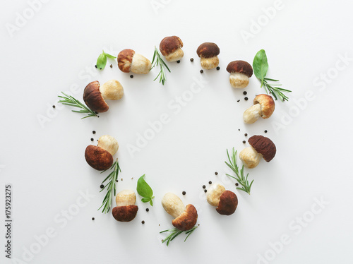 white mushrooms with basil, rosemary and pepper on white table