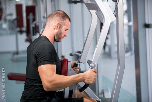 muscular man working on fitness machine at the gym