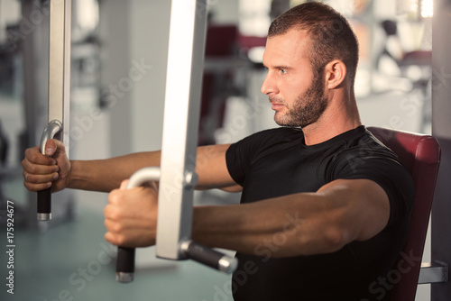 muscular man working on fitness machine at the gym © fotoinfot