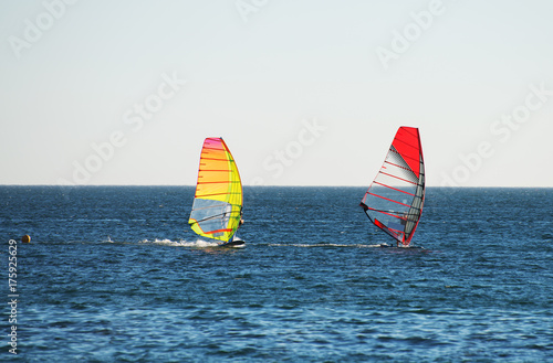 Two people windsurfing in the sea.