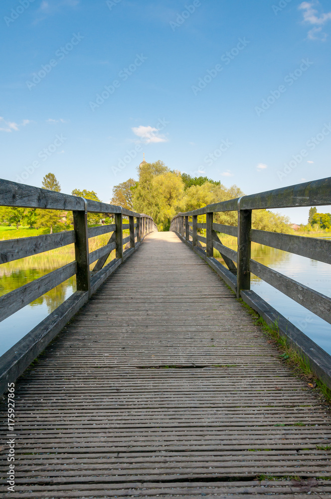 Obraz premium boradwalk with rails over lake with trees in the background