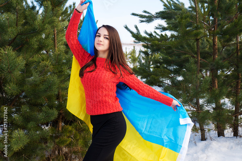 A young cute girl holds a flag of Ukraine.