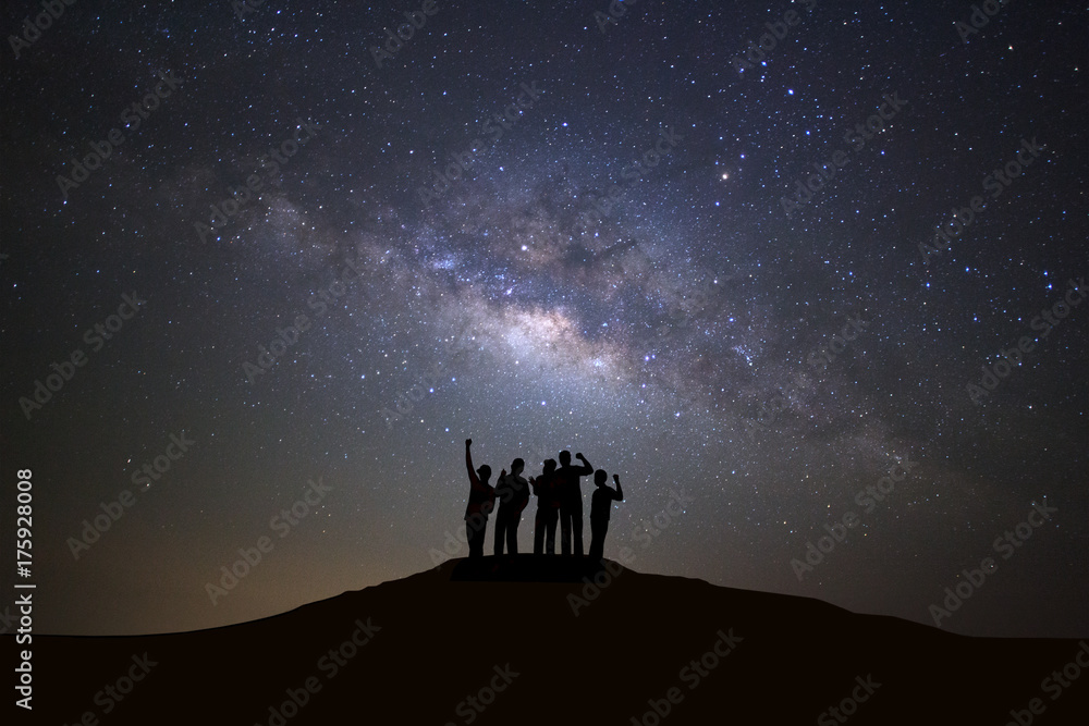 Fototapeta premium Krajobraz z galaktyką drogi mlecznej, rozgwieżdżone nocne niebo z gwiazdami i sylwetka ludzi stojących szczęśliwego człowieka na wysokiej górze.