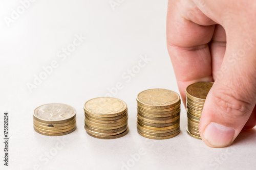 Piles of metal coins isolated above white background and hand holding pile of coins