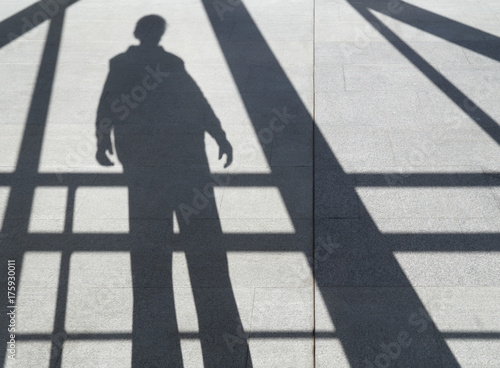 shadow of a man on the sidewalk among the beams
