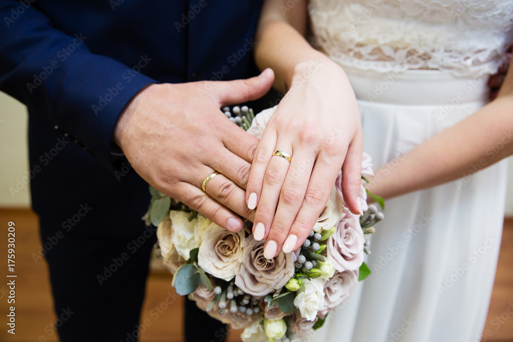 Bride and groom hands with wedding rings and bridal bouquet Bride and groom hands with wedding rings and bridal bouquet