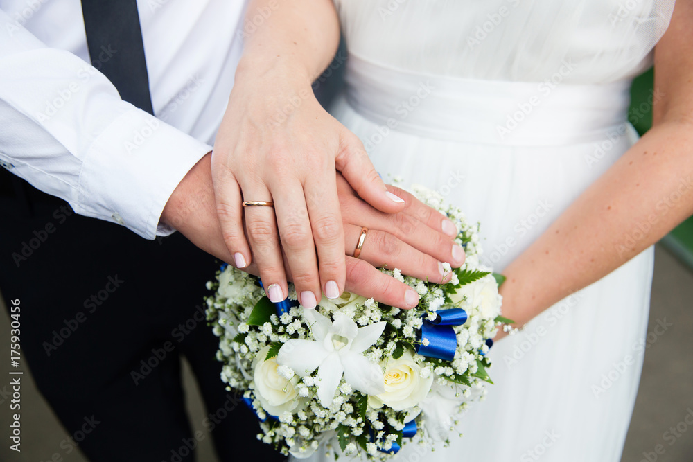 Bride and groom hands with wedding rings and bridal bouquet Bride and groom hands with wedding rings and bridal bouquet