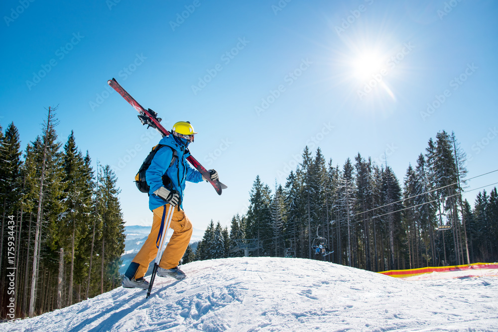 Shot of a male skier walking up the slope in the mountains carrying his gear on his shoulder on a sunny day at winter resort copyspace active lifestyle equipment skiing concept