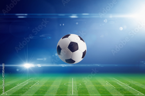 Soccer ball on soccer stadium with bright light flare in night