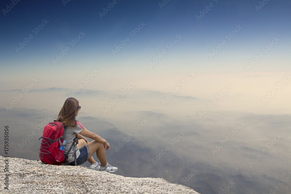 Traveling woman sitting near mountain and looking