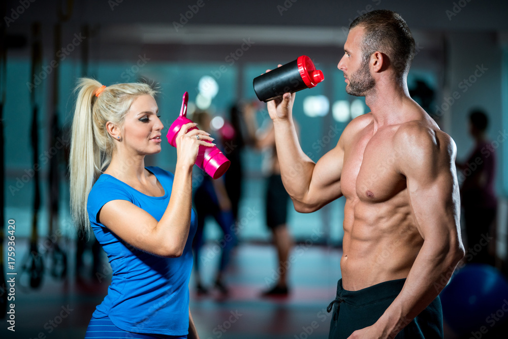 man and woman with protein shake at gym Photos | Adobe Stock